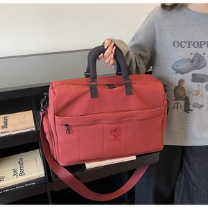 Detail of red travel bag featuring reinforced handles and a sturdy shoulder strap