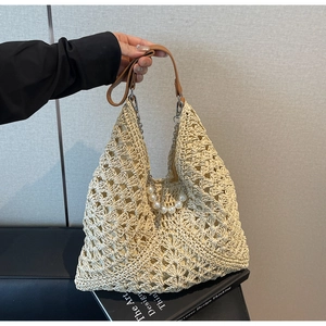 Détail du sac cabas en paille avec chaîne de perles et poignées en cuir marron