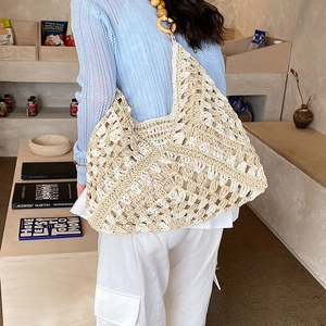 Dettaglio della borsa tote in maglia traforata con perline in legno sul manico