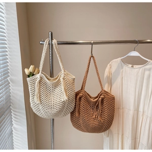 Detail of cream and brown handmade knit tote bags with tassels for summer vacations