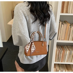 Detail of brown crocodile pattern handbag with houndstooth scarf and silver fashion text