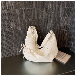 Detail van gebroken witte hobo tas met zilveren sterrenprint en zijtrekkoord
