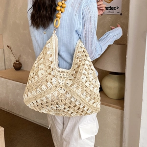 Dettaglio della borsa tote intrecciata con tracolla decorativa in perline di legno naturale