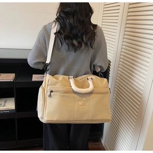 Detail of light khaki quilted travel bag with adjustable strap in home setting