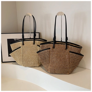 Detail of woven straw tote bags in beige and brown with elegant black leather straps