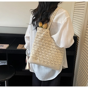 Detail of cream crochet shoulder bag showing intricate wavy knit and braided strap