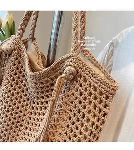 Detail of woven shoulder strap and hollow knit texture on large beige straw beach bag