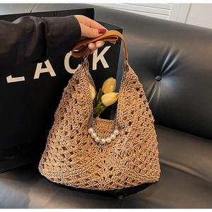 Détail du sac cabas en paille tissée avec chaîne de perles et poignée en cuir