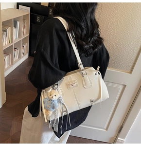 Detailed view of cream white tote bag featuring a cute blue sweater bear charm accessory