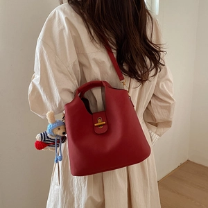 Sac fourre-tout en cuir rouge avec fermoir doré et pendentif lapin porté avec robe blanche