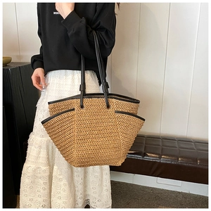 Detail of woven straw tote bag with black faux leather trim and side pocket texture