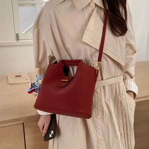 Gros plan d'un sac seau vintage en cuir rouge foncé avec un fermoir rotatif en métal doré