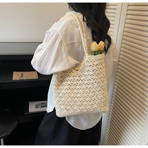 Detail of the woven hollow pattern and braided shoulder strap on the beige tote bag