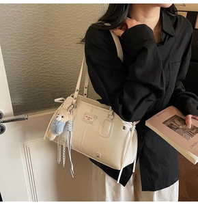 Chic cream tote bag with bear charm detail shown on model in a minimalist setting