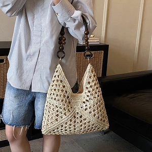 Dettaglio della borsa tote in paglia intrecciata con tracolla decorativa in perline di legno