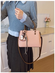 Detail of pink canvas handbag with brown leather handles and cute white horse charm