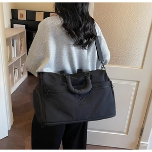 Close-up of black NINGJIA travel duffel bag with reinforced handles and adjustable strap