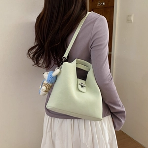 Détail du sac seau vert clair avec breloque ours porté en sac à bandoulière croisée
