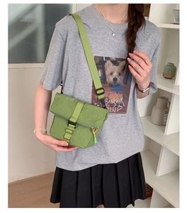 Sac à bandoulière réglable à carreaux verts avec boucle à rabat porté par un modèle