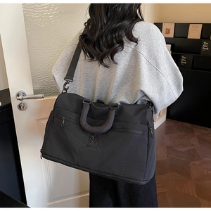 Detail of reinforced black travel bag handle and adjustable shoulder strap for durability