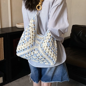 Dettaglio borsa tote intrecciata blu e beige con manico in legno e motivo floreale