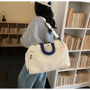 Detail of off-white travel bag with blue handles and NINGDA logo in a library setting