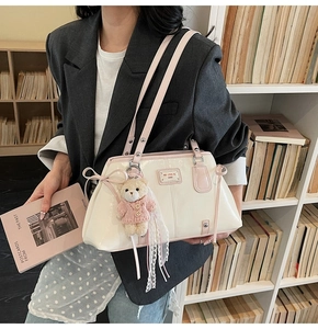 Close-up of a white patent leather shoulder bag with pink bow and cute bear keychain
