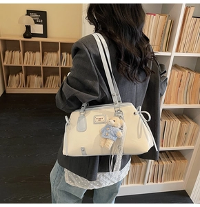 Detail of vintage beige shoulder bag with blue trim and cute teddy bear pendant