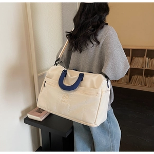 Detail of a large cream and navy canvas duffel bag with embroidered shield logo