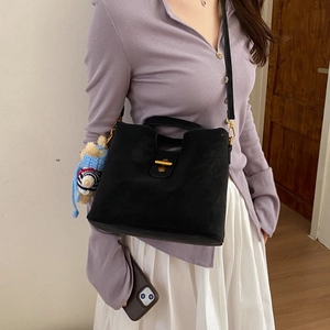 Détail du sac bandoulière en daim noir avec fermoir doré et charm ours bleu