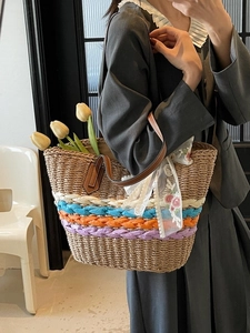 Strohtasche mit bunten Streifen und Lederriemen, von einem Model getragen