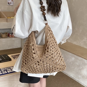 Dettaglio della borsa tote in paglia intrecciata con tracolla in perline di legno scuro