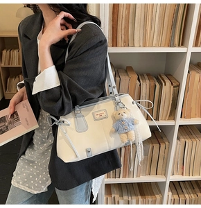 Detail of white and blue shoulder bag featuring a cute bear charm and bow decoration