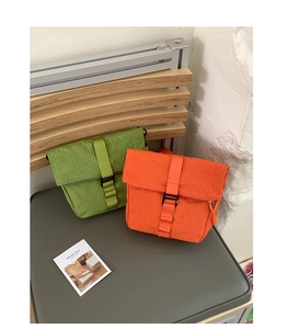 Détail des sacs bandoulière imperméables vert et orange en nylon à texture quadrillée