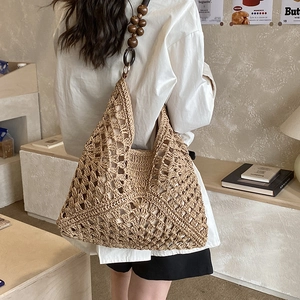 Dettaglio della borsa tote in paglia intrecciata con spalline in perline di legno scuro