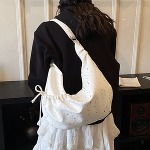 Detailweergave van witte hobo-tas met zilveren sterrenprint en veters aan de zijkant