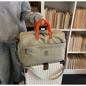 Detail of large capacity travel bag with orange handle on a white suitcase