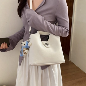 Détail du sac seau en cuir blanc avec fermoir argenté et accessoire de charme ours en peluche