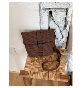 Vue détaillée du sac bandoulière imperméable à carreaux marron sur un tabouret