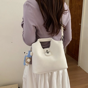 Détail du sac seau en cuir blanc avec fermoir rotatif argenté et breloque ours bleue