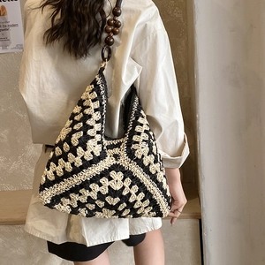 Dettaglio della borsa tote intrecciata con motivo geometrico e tracolla in perline di legno marrone