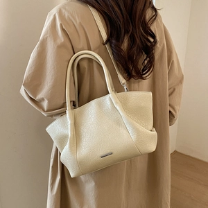 Vista detallada del bolso tote de cuero sintético crema con textura arrugada en abrigo beige