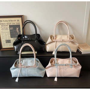 Sacs à main minimalistes en similicuir en noir, crème, bleu et rose disposés sur marches