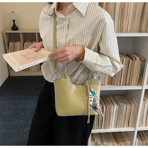 Detail showing high-quality leather bucket bag with decorative keychain and silk ribbon