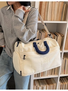 Quilted off-white large travel duffel bag with blue handles and adjustable shoulder strap