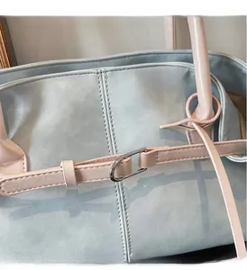 Détail de la couture en cuir et de la boucle argentée sur un grand sac cabas bicolore