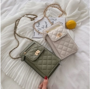 Close-up of diamond quilted crossbody phone bags in green and beige with gold chain