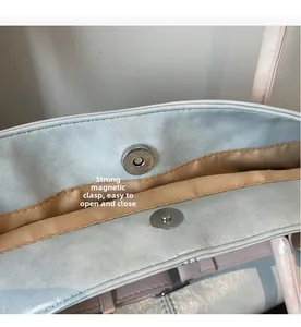 Détail de la boucle magnétique puissante sur ce sac cabas en cuir texturé bleu