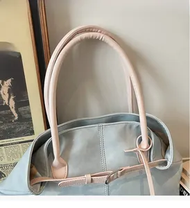 Vue détaillée du sac cabas en similicuir bleu clair avec des anses roses robustes