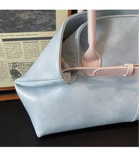 Gros plan détaillé de la texture du cuir bleu-gris et de la sangle de ce sac cabas